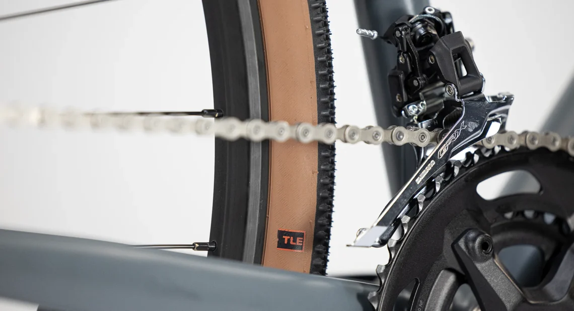 Dettaglio della trasmissione della bicicletta Lombardo Maranello, mostrando il deragliatore anteriore SRAM e la catena in movimento, con il copertone marrone in evidenza, progettato per offrire prestazioni elevate e affidabilità.