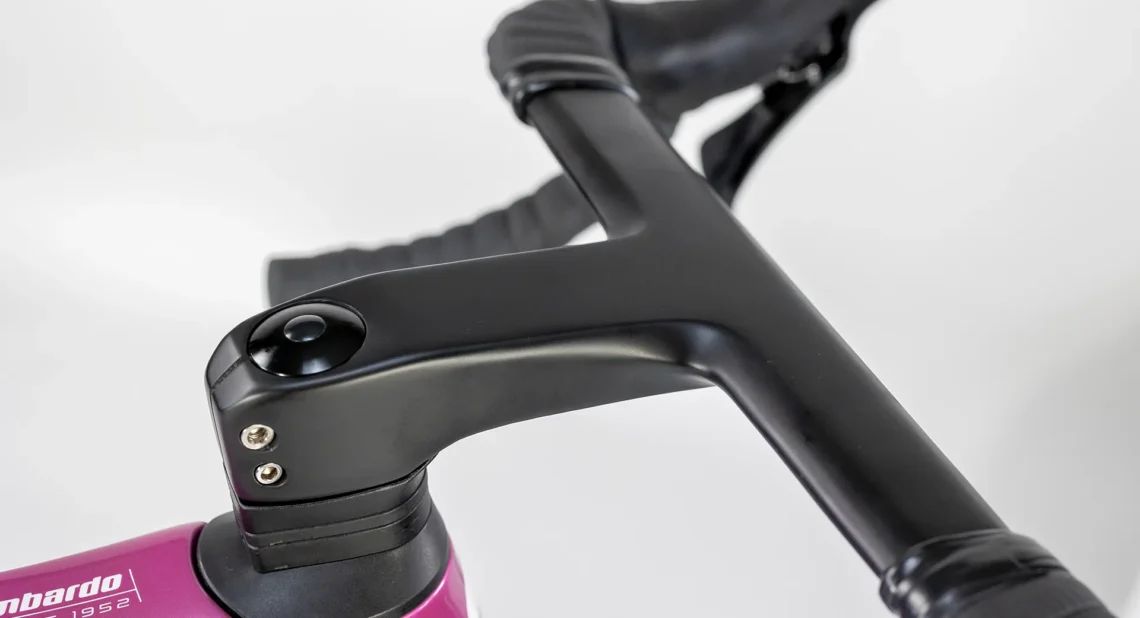 Dettaglio della piastra del manubrio della bicicletta Lombardo, evidenziando il design elegante e funzionale. Mostra il colore viola del telaio in combinazione con il manubrio nero